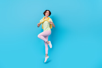 Full size photo of pretty young brunette lady jump wear t-shirt pants shoes isolated on blue background