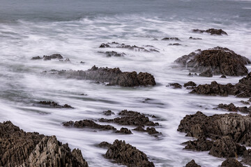 A rocky North Devon coastline, lapped by waves.  A long exposure brings motion and atmosphere.