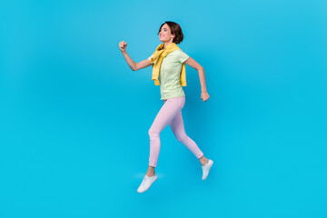 Fototapeta na wymiar Full body profile photo of impressed millennial brunette lady run wear t-shirt trousers sneakers isolated on blue background