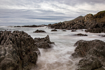 Obraz premium Dramatic rocks in the sea in North Devon, with a cool November sky. A long exposure adds movement and mystery.