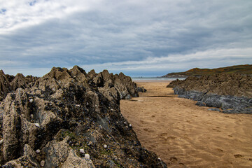 Low tide reveals this rocky beach with channels of sand leading to the sea.  The sky is a little stormy, on a chilly April day.  Mortehoe, near Woolacombe, North Devon.