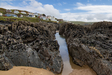 The Western edge of Woolacombe from the rocky beach below.  The rocks are covered in shell fish and a water channel leads up towards the houses on the hill.