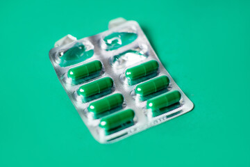 Started packing of tablets with green capsules. Green background. Probiotics, vitamins concept.