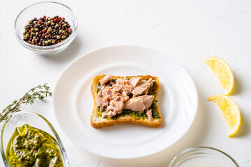 Toast with chimichurri sauce and tuna on a white plate. White background. Minimalistic design. Useful snack.