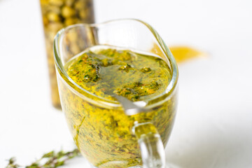Chimichurri sauce in a gravy bowl on a white background. Argentinean vegetarian sauce made from olive oil, oregano, parsley.