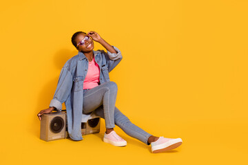 Full length portrait of satisfied glad person sitting boom box hand touch glasses isolated on yellow color background