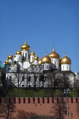 Fototapeta na wymiar Assumption Cathedral, Annunciation Cathedral with golden cupolas behind the Kremlin wall view from embankment of the Moscow river front view