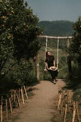 Woman is swinging on swings in orange farm in Mon Jam