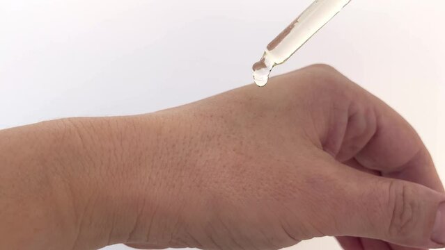 Close-up of women's hands holding a cone with cosmetic oil for the body and hands, a drop of oil dripping onto the skin.