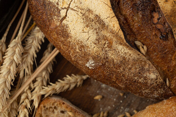 Close-up of homemade bread. Peasant loaf bread and wheat spikelet with space for text. Homemade baking. Gray whole bread on wooden board.