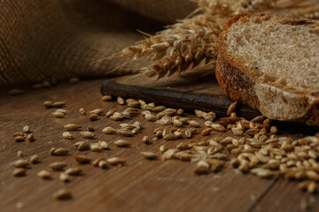 Close-up of homemade bread. Peasant loaf bread and wheat spikelet with space for text. Homemade baking. Gray whole bread on wooden board.