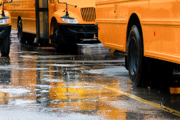 A heavy spring rain comes down in buckets in Windsor in Upstate NY. Reflection of the yellow school bus can be seen in the puddle in the parking lot of the School.