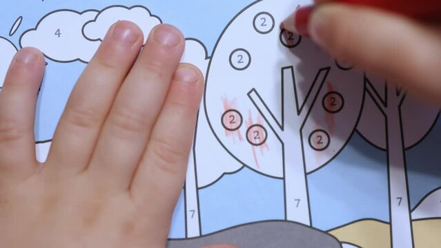 close-up view baby child hands coloring book with pencils numbers color crayons. unrecognizable caucasian little kid fingers holding pencil trying hard to draw paint dots picture. coloring tree fruits