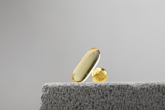 Yellow oil capsules with vitamin D on grey background. Omega 3 tablet. Healthy diet concept
