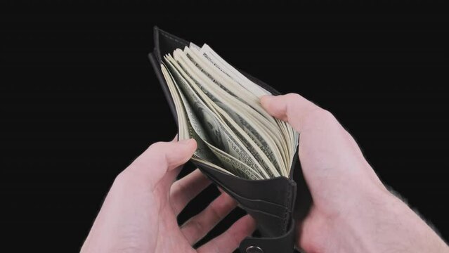 Male hands show a black wallet full of 100 dollar bills on alpha channel. Stack of American banknotes in wallet. Concept of financial well-being, wealth, profit, budget. Checking money. Chroma key. 4K