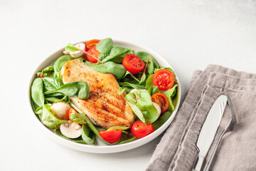 Fresh salad - spinach leaves, tomato, mushrooms, chards leaves and chicken fillet grill in a plate on the table. Top view. Healthy diet food.