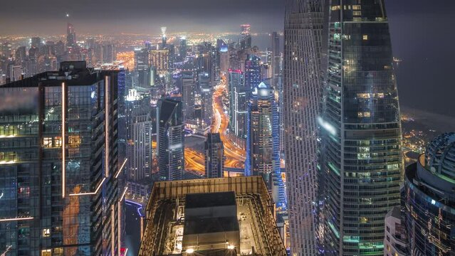 Skyline panoramic view of Dubai Marina showing canal surrounded by skyscrapers along shoreline all night timelapse. DUBAI, UAE