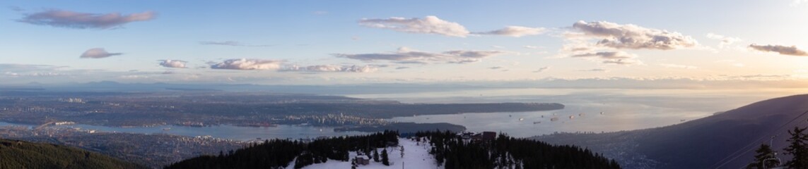 View of Top of Grouse Mountain Ski Resort with the City in the background. North Vancouver, British Columbia, Canada. Sunset Sky