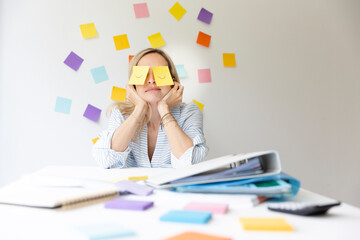 Business woman sits behind her desk on which are many office things and has sticky notes with drawn...