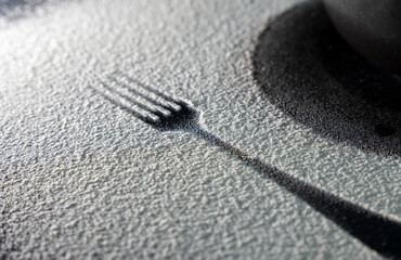 Fototapeta na wymiar Top view of spoon and fork silhouette made with flour and egg on dark background. Egg and whisk on white flour. Rustic contrasting background. Food preparation process. Concept of bakery.