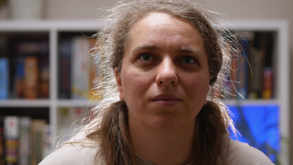A close-up of the face of a young Caucasian girl with a serious look on the background of a rack of...