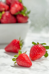 Fresh ripe organic strawberries in a white cup on white table
