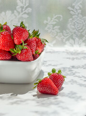 Fresh ripe organic strawberries in a white cup on white table