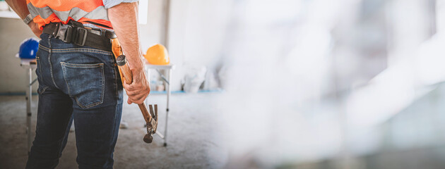 Architect man confident holding hammer in hands at site work, image panorama for banner cover design.