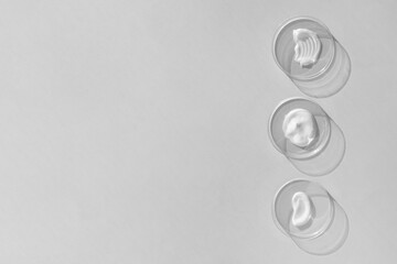 White cream textures in Petri dishes on a gray background. Concept of cosmetics laboratory researches. Smear of skincare cosmetics product. Wellness and beauty concept. Soft focus