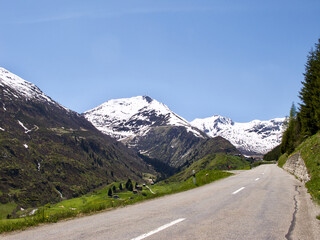 Road with a view over snowy mountain and a green valley in Switzerland.