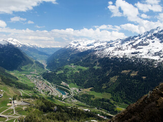 Fototapeta premium Landscape with a view over a village in the Urseren valley between snowy mountain in Switzerland in spring.