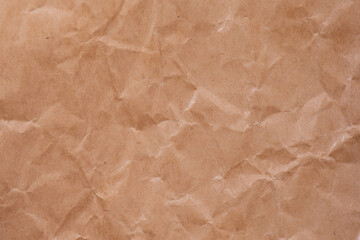 Wrinkled brown paper background. Abstract background of crumpled wrapping paper close-up macro shot. Textured recyclable natural packaging paper.