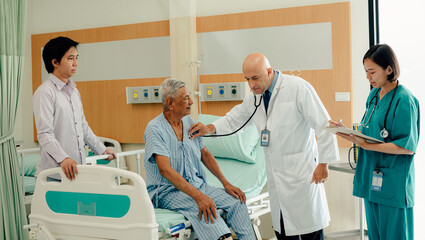 Obraz premium Hospitalized man sitting in bed while doctor checking his pulse. Doctor examining senior male patient in hospital room.