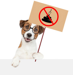  Smart Jack russell terrier puppy wearing eyeglasses holds sign "no dog poop" above empty white banner. Concept cleaning up dog droppings. Isolated on white background