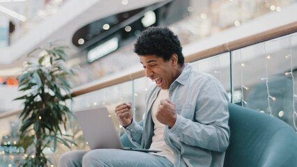 Side view african guy male user online gambler plays betting game on internet receives cash prize wins screams from success triumph victory. Man student receives message about admission to university.