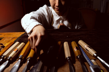 young Chinese woman violin maker is choosing suitable tools for making the violin
