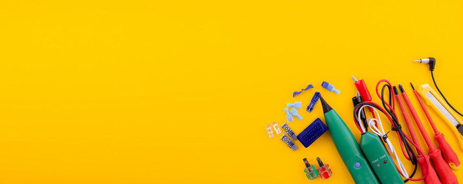 Arrangement of tools for repairing automotive electrical wiring on a yellow background. - Powered by Adobe