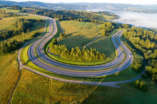 Poland. Winding switchback road from Krakow to Zakopane, called Zakopianka, near Rabka and Chabowka. Aerial view in sunrise light with morning fog