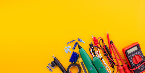 Arrangement of tools for repairing automotive electrical wiring on a yellow background.
