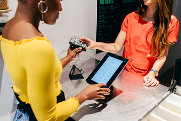 Woman paying with smartphone at cafe counter