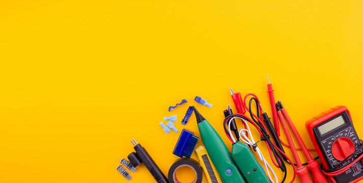 Arrangement of tools for repairing automotive electrical wiring on a yellow background.