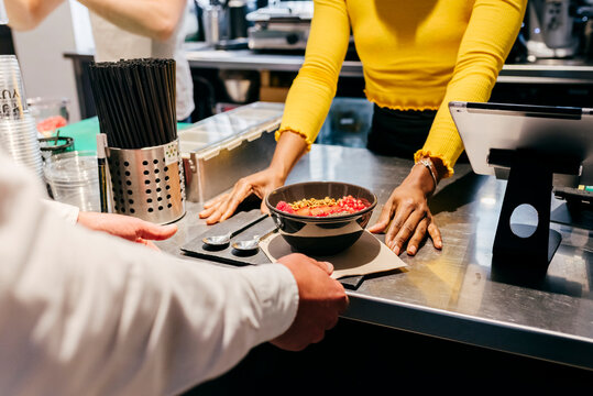 Waitress serving smoothie bowl at cafe counter