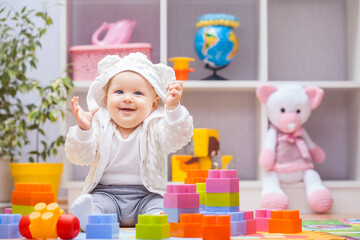 baby girl playing with colourful building blocks at home or kindergarten