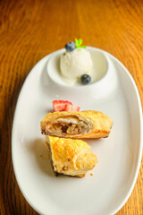 A piece of apple strudel with vanilla ice cream and strawberries