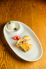 A piece of apple strudel with vanilla ice cream and strawberries