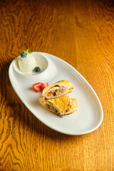 A piece of apple strudel with vanilla ice cream and strawberries