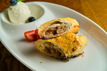 A piece of apple strudel with vanilla ice cream and strawberries