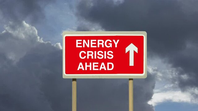 Zoom in to a road sign indicating an approaching Energy Crisis with a background of timelapse clouds. A worldwide shortage of fuel of gas and oil.