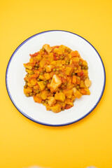 squid stew with vegetables in white dish on yellow