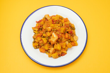 squid stew with vegetables in white dish on yellow